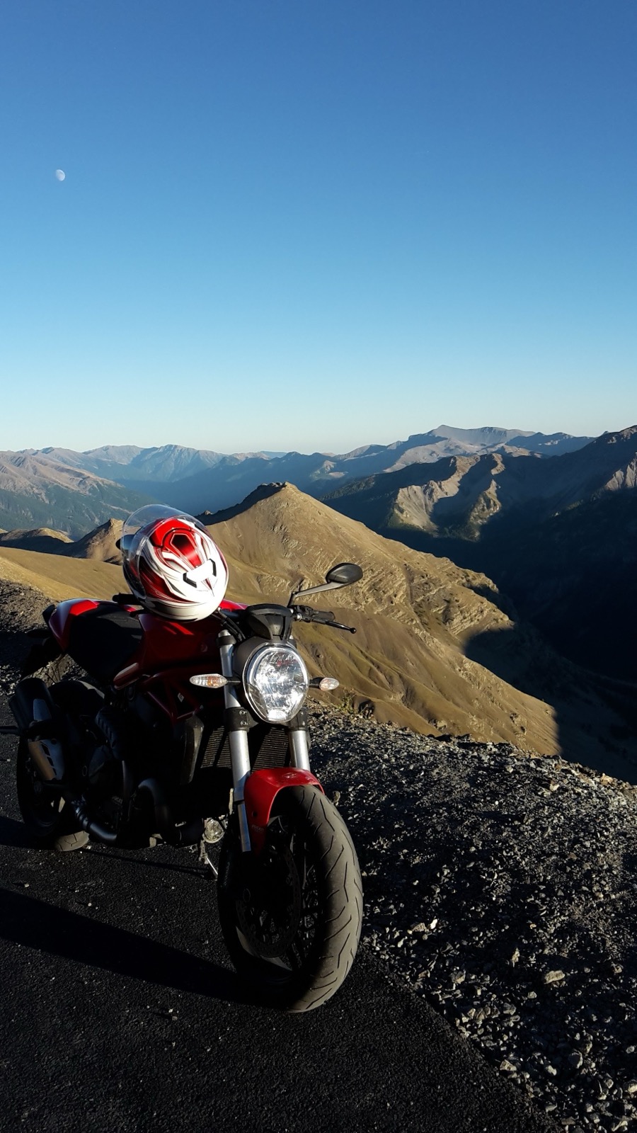 Ducati Monster motorcycle on a mountain pass at dusk with moon